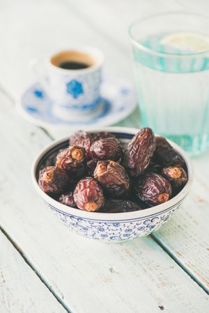 Bowl of dates with espresso and water in background