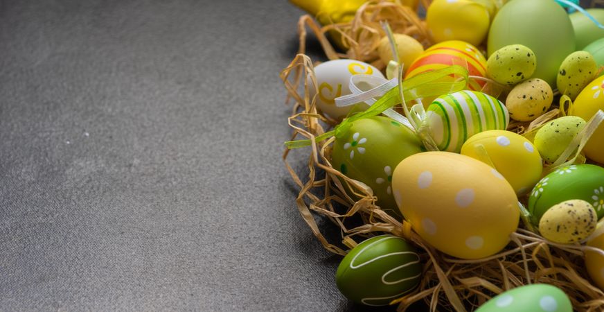 Easter decorations scattered in straw on grey table