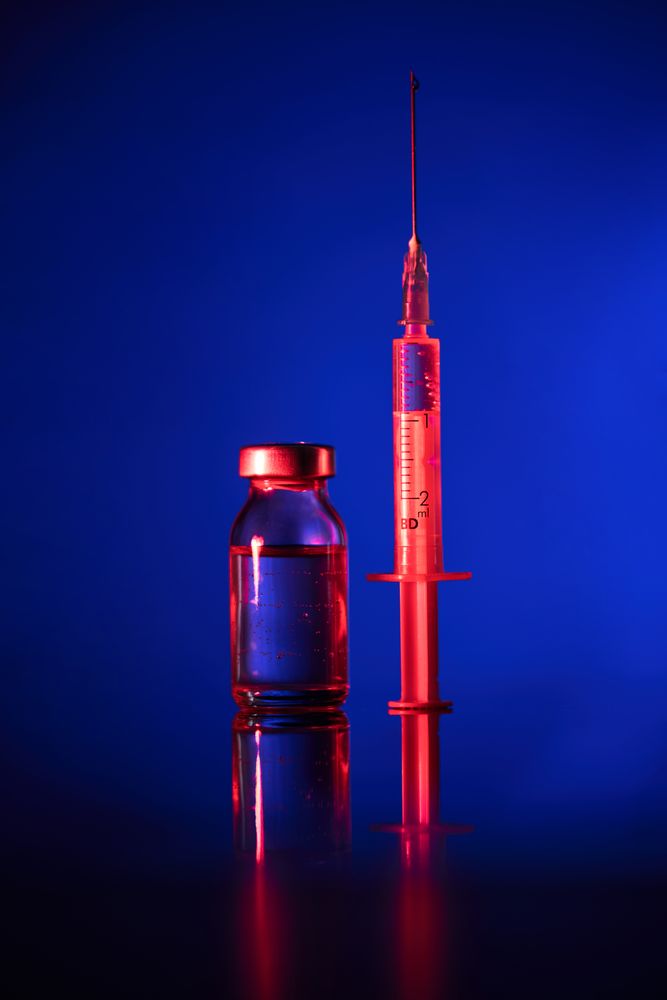 Vial and syringe with vaccine in dark room