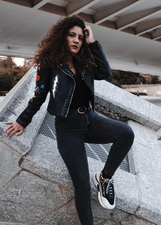 Modern woman in jacket and jeans standing in city