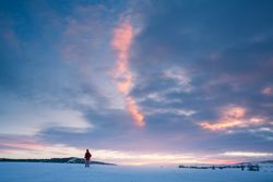 Traveler standing on snow against sunset sky