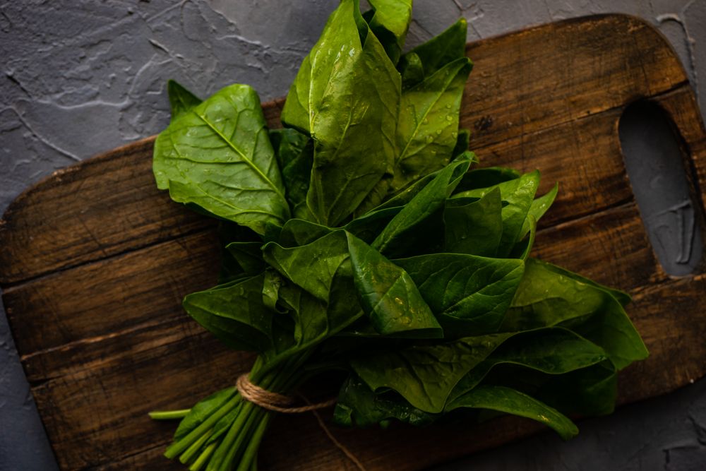 Fresh spinach wrapped on breadboard