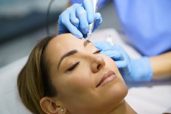 Woman having permanent make-up applied to eyebrows