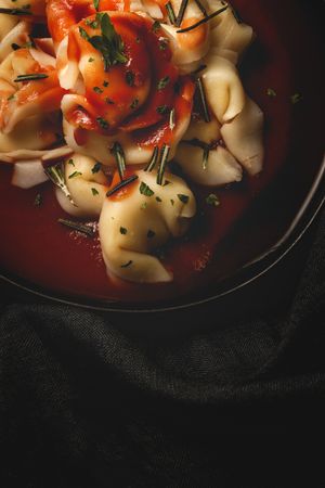Plate of delicious ravioli with tomato sauce served on table
