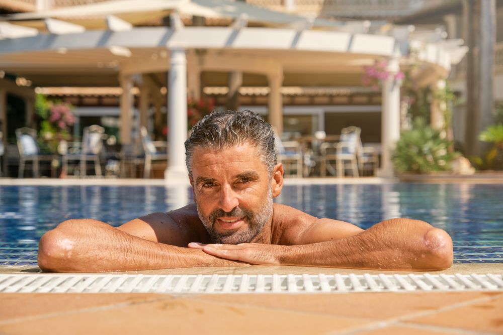 Handsome adult man resting in pool at resort