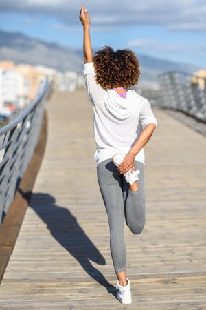 Back view of woman standing doing quad stretch