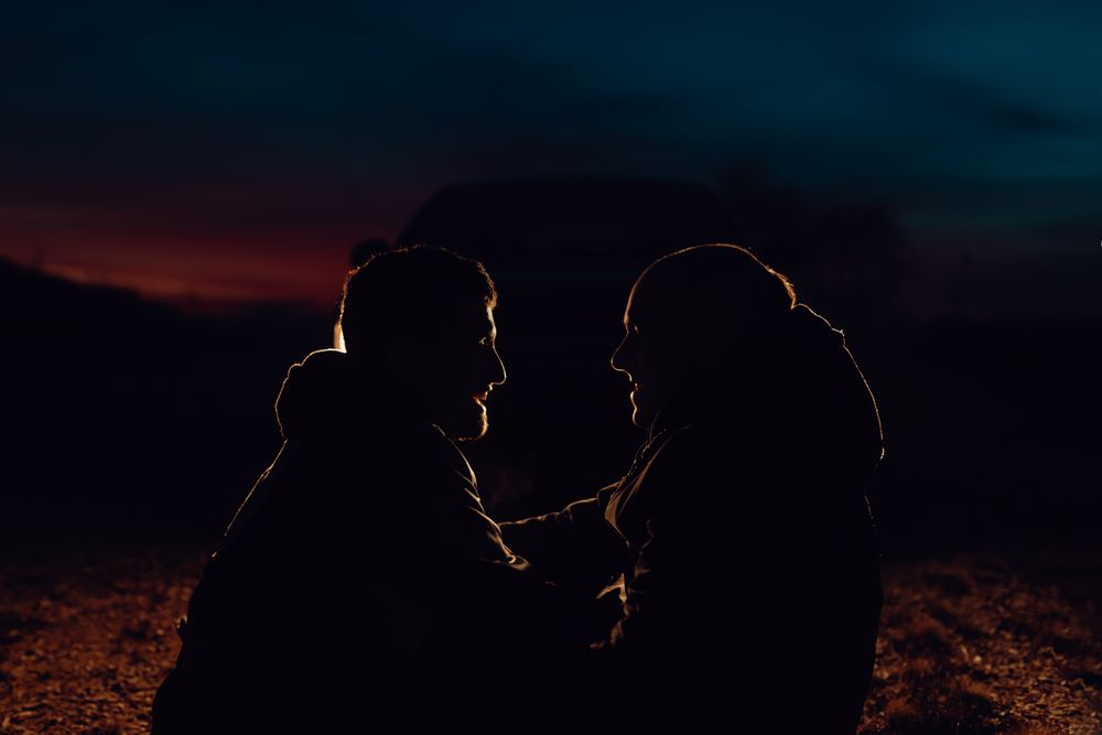 Men hugging and sitting on ground on field at night
