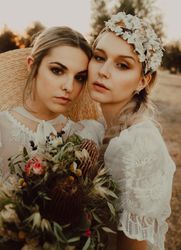Charming slim brides with flowers in garden with olive trees