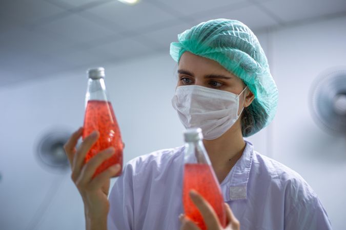 Woman worker inspecting on juice bottle wearing a hairnet