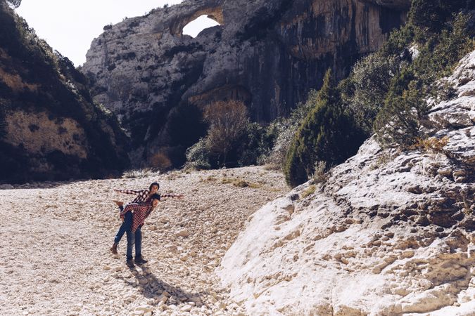 Woman and man having fun on stones between high hills