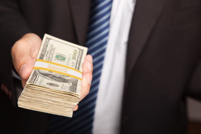 Businessman Handing Over Stack of Cash