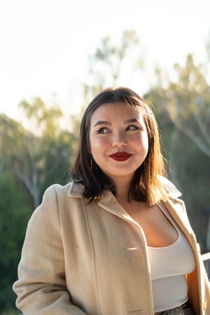 Young woman outside smiling and looking to the side with her eyes