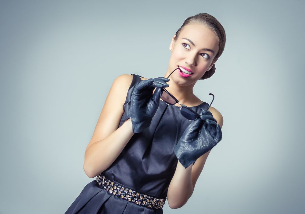 Vintage fashion model holding sunglasses to mouth