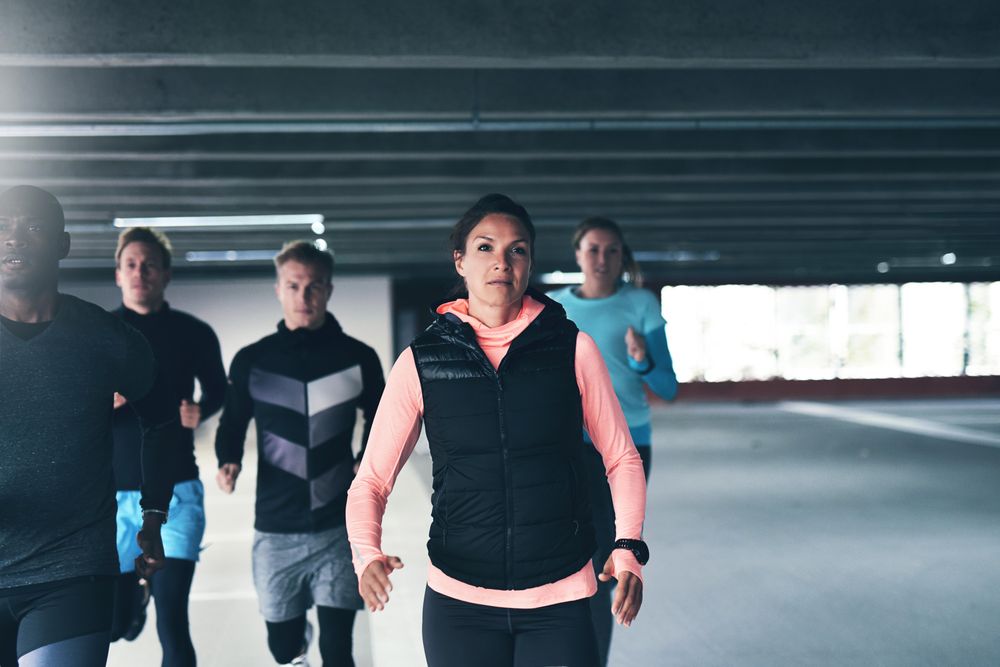 Group of athletic men and women running in concrete space