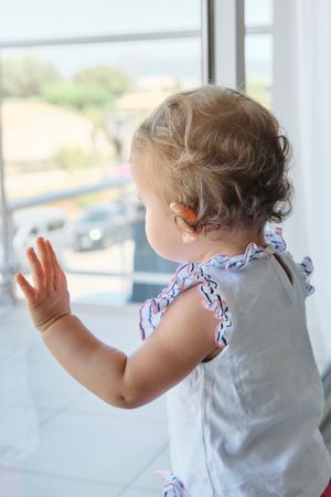Adorable toddler looking out window with interest