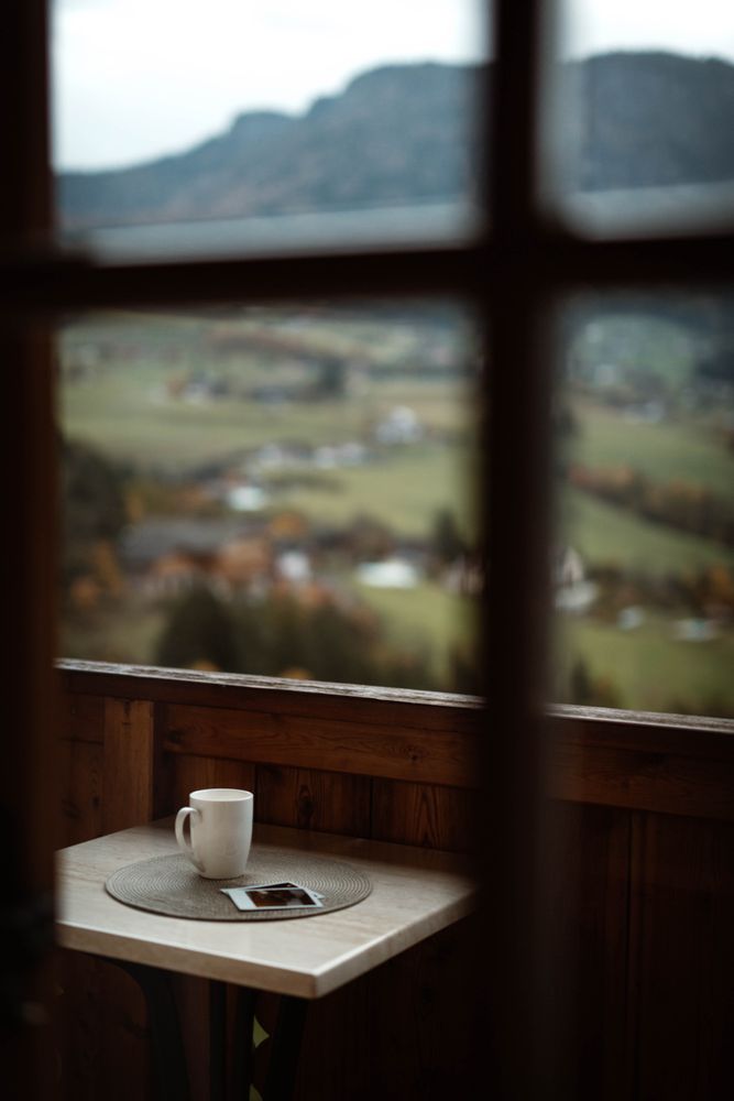 Small table with cup of coffee and photos on terrace on cloudy morning