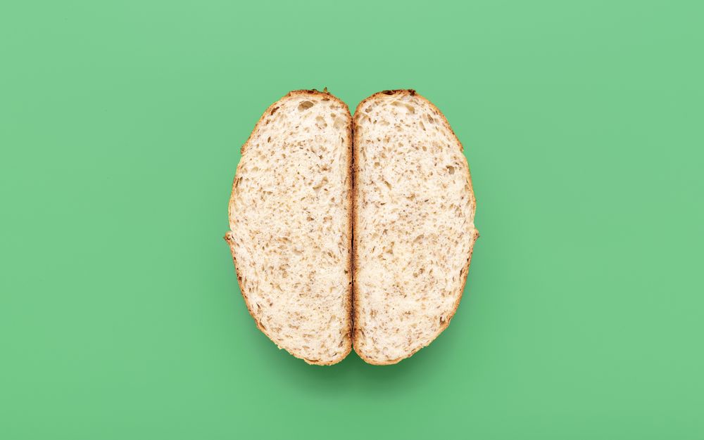 Bread with sesame seeds sliced in two, above view on a green background