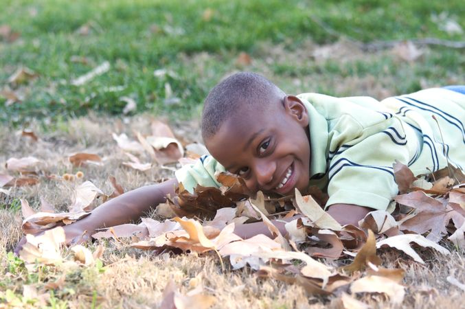 Young Boy Playing In Fallen Leaves