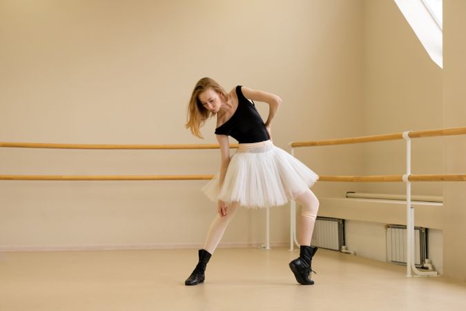 Ballerina in shoes and tutu, bending in modern dance