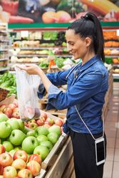 Delightful woman buying apples in grocery store