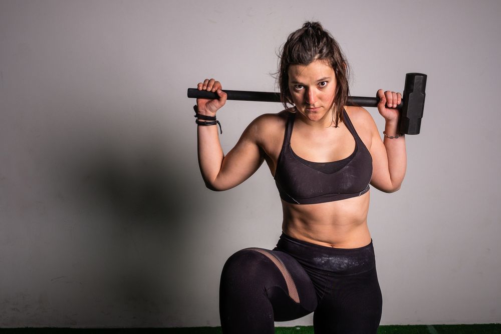 woman with hammer hitting on tire in gym