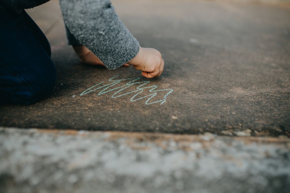 Child drawing squiggles with chalk outside