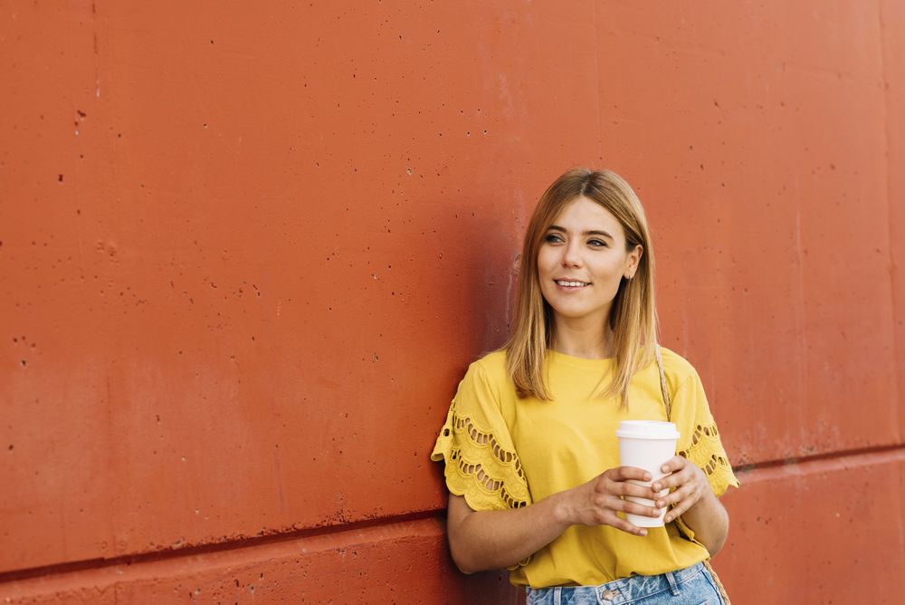 Young blonde woman drinking takeaway coffee