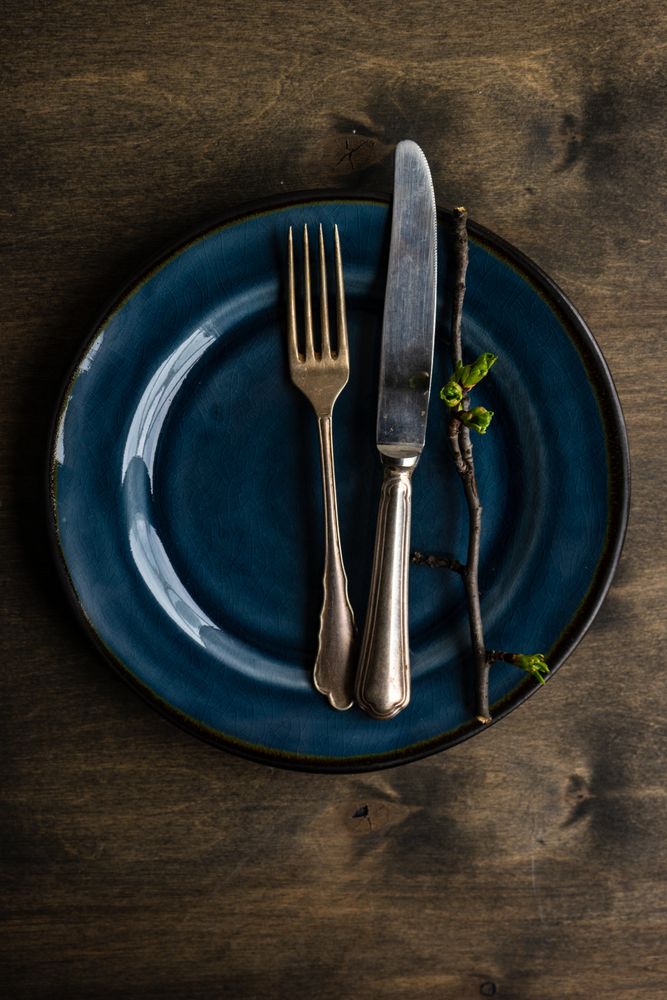 Spring table setting of navy plate decorated with cherry bloom tree branches