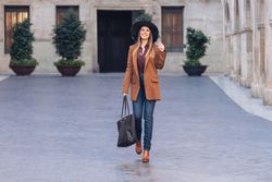 Gorgeous woman in fashionable outfit strolling on city street