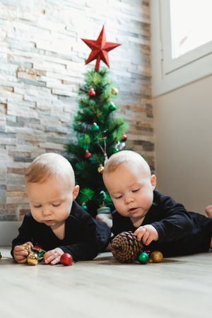 Twins on floor near Christmas tree