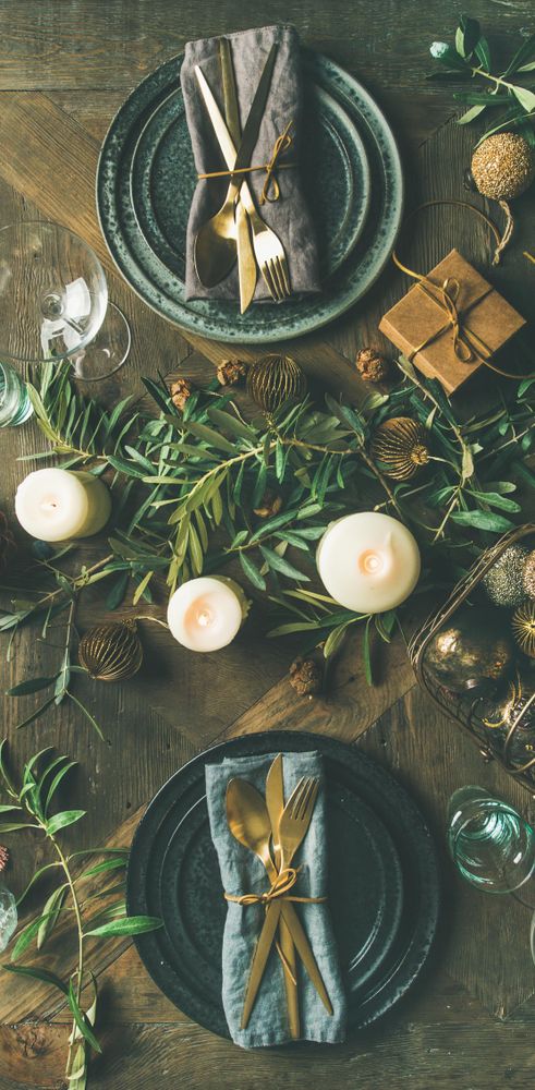 Festival holiday table setting on wooden table, with gold ornaments and branches, narrow composition