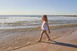 a little girl at the seashore entering the water