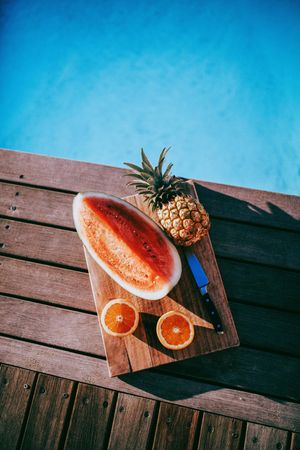 Fruit platter on a wooden board by the pool on a sunny day