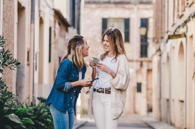 Friends walking and smiling with smartphone