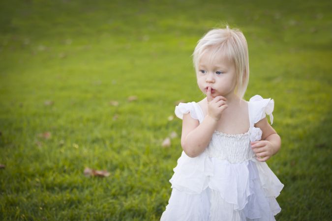 Adorable Little Girl Wearing Dress In A Grass Field