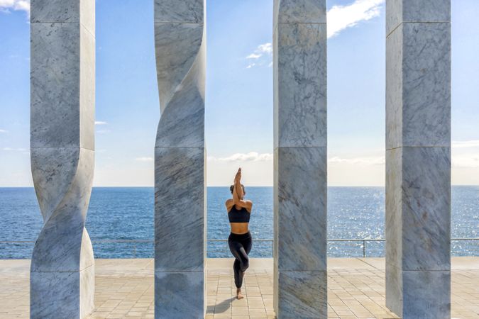 Female doing yoga between sculpture with view of horizon