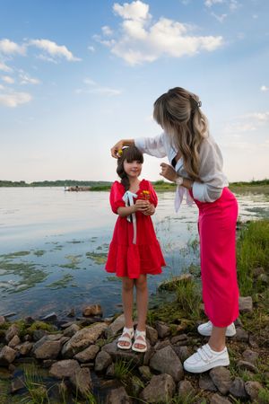 Mom and little daughter walking by the lake or pond