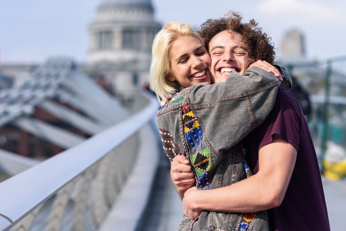 Male and female hugging on bridge in London