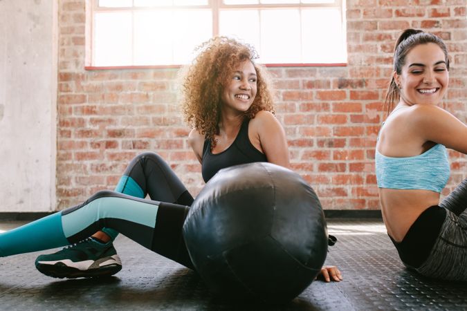 Two female friends smiling and taking break from workout