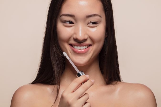 Close up of smiling young woman holding lip applicator