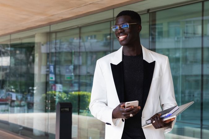 Stylish Black businessman using smartphone in city