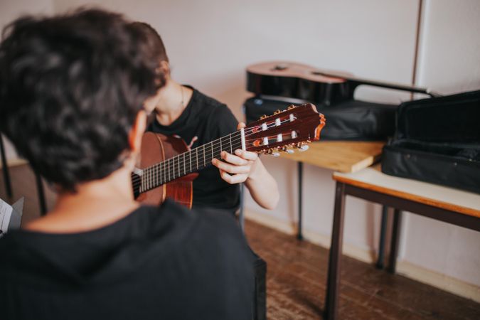 Young student performing guitar solo for music class