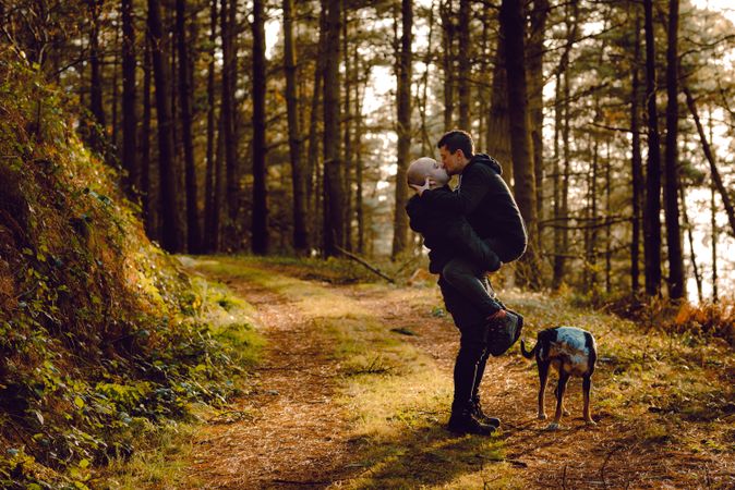Men hugging and kissing on countryside road near dog