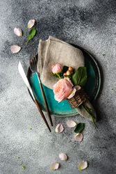 Top view pink flowers on grey napkin and teal plate