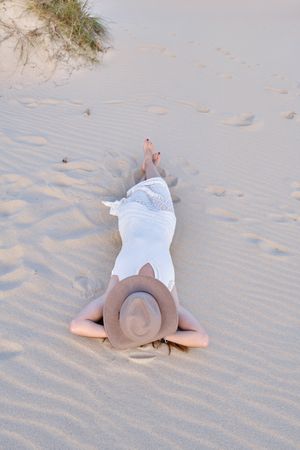 Woman in white dress relaxing on sand