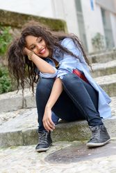Happy female with curly hair sitting on cement stairs outside