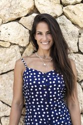 Portrait of hispanic woman in blue dress in front of wall
