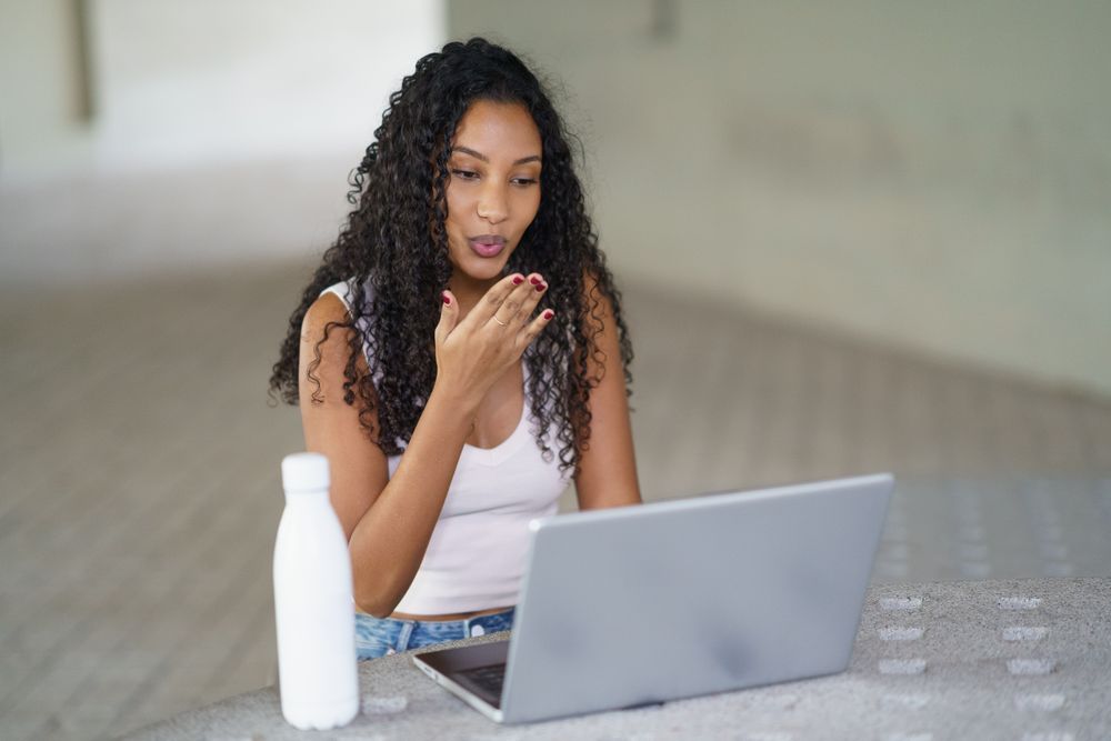 A Young Woman is Actively Engaged in an Online Conversation While Using Her Laptop