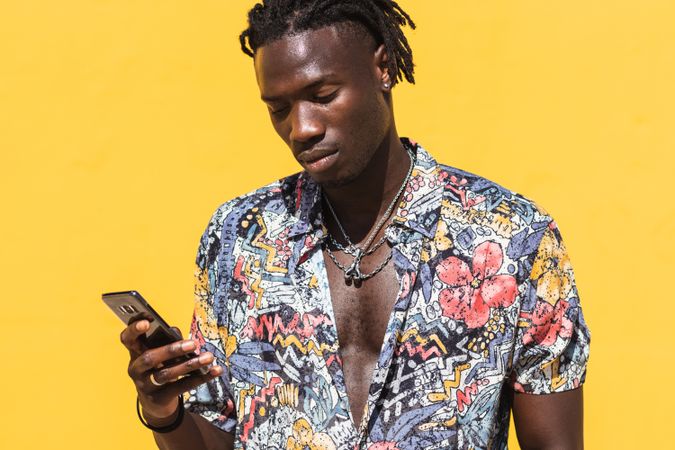 Stylish Black man in colorful shirt with smartphone