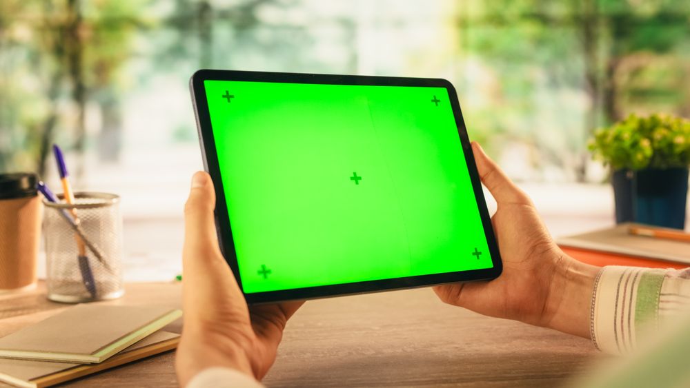 Anonymous Man Holding Tablet Computer with Green Screen Mock Up Display, Sitting Behind a Wooden Desk in a Creative Agency. Photo Template for Digital Presentations, Communication Materials